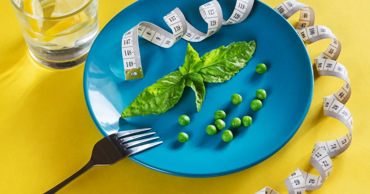 a blue plate topped with green vegetables and measuring tape