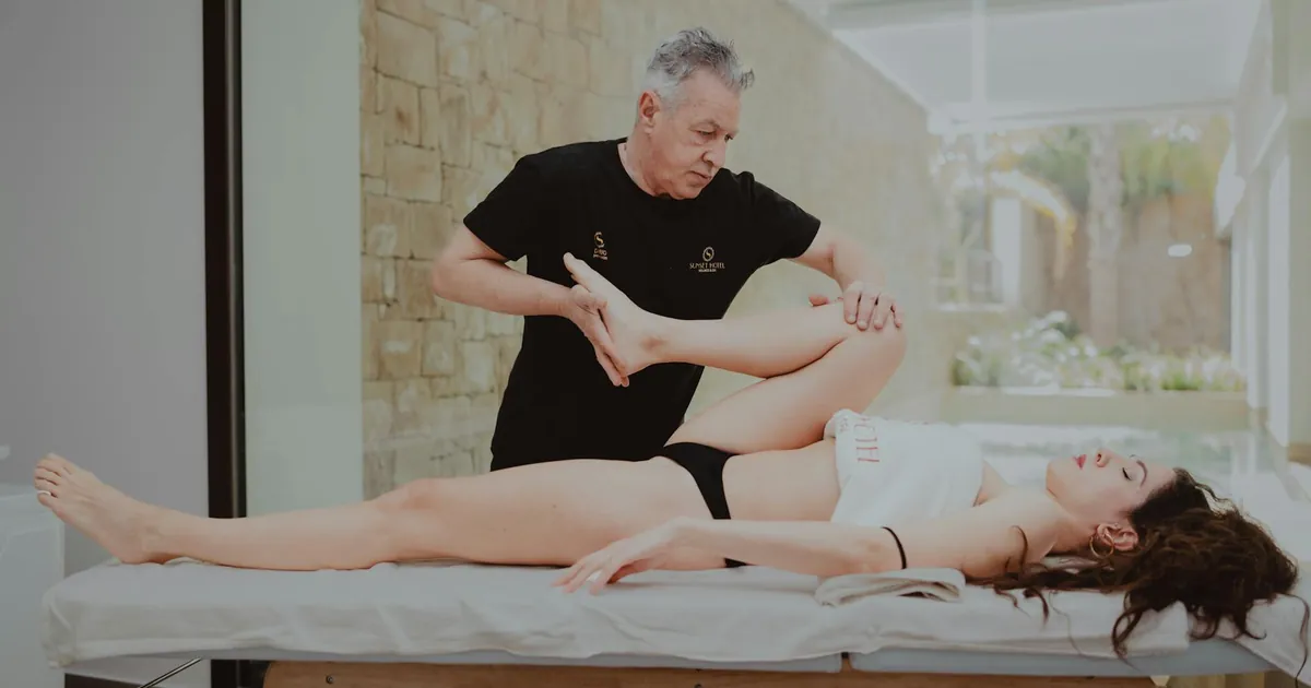 A therapist assists a patient during a rehabilitation session indoors, promoting mobility and flexibility.