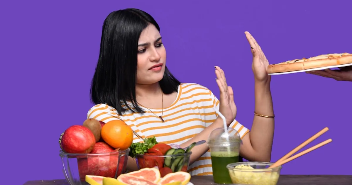 a woman sitting at a table with food and a bowl of fruit a woman sitting at a table with food and a bowl of fruit