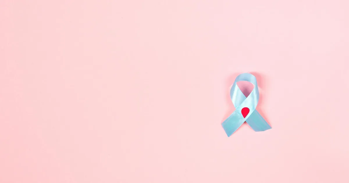 A blue ribbon symbolizing diabetes awareness on a soft pink background, offering ample copy space.