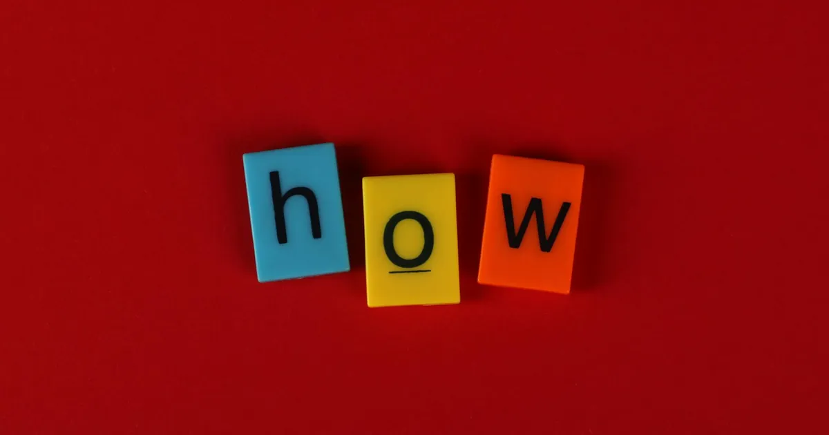 Colorful letter tiles spelling 'How' on a vibrant red background, ideal for educational content.