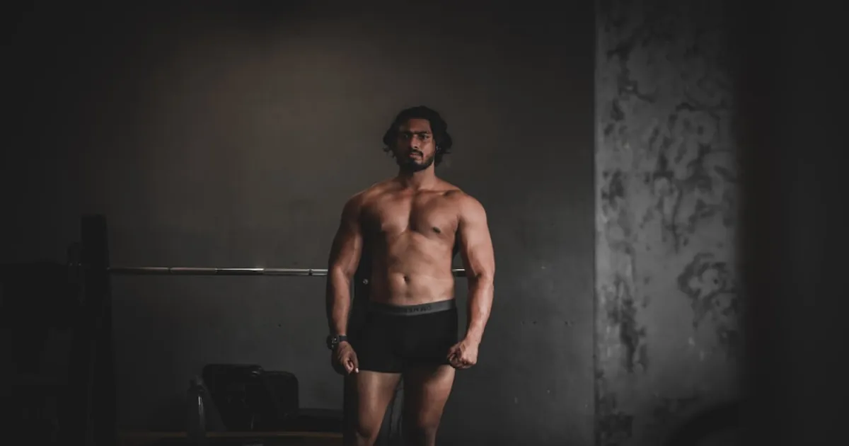 topless man in black shorts standing on brown wooden floor