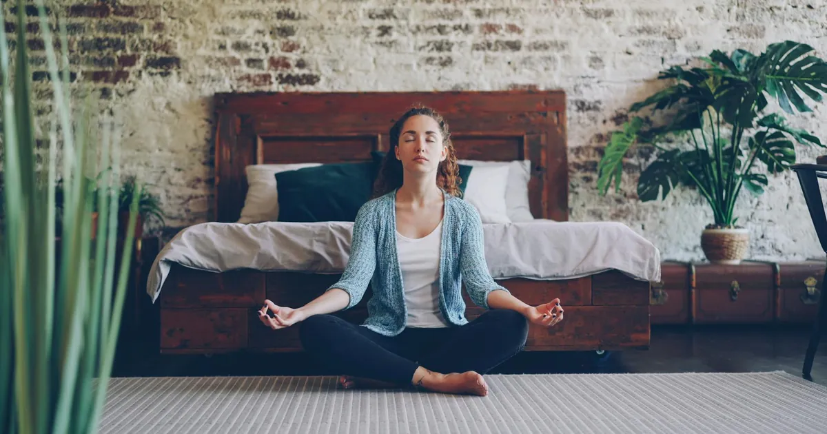 Tranquil scene of a woman meditating in a stylish bedroom with natural decor. Tranquil scene of a woman meditating in a stylish bedroom with natural decor.
