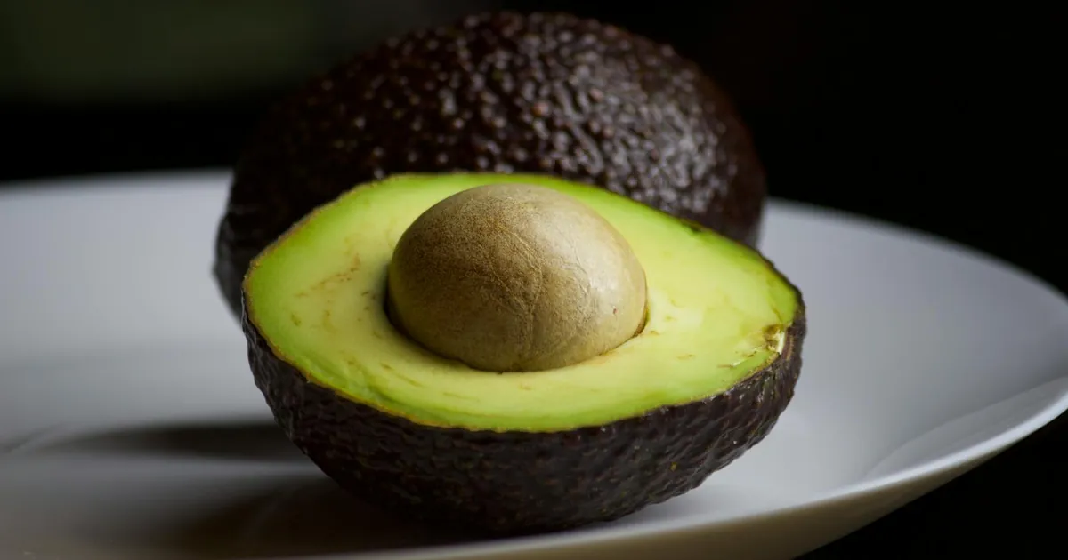 Ripe halved avocado on a plate showcasing its vibrant green flesh and seed.