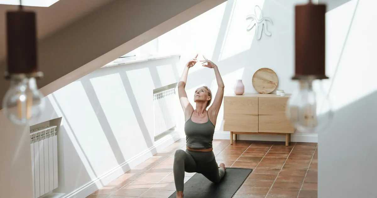 Senior woman stretches gracefully in an inviting sunlit room, embodying a healthy lifestyle.