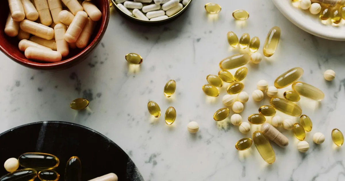 A flat lay of diverse capsules and supplements on a marble countertop, showcasing health and wellness products.