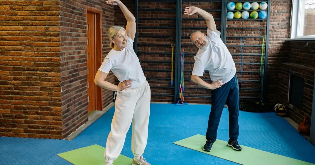 Elderly couple stretching on yoga mats in a home gym, embracing a healthy lifestyle.
